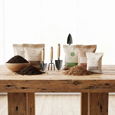 Gardening tools and organic amendments like compost and fertilizer on a wooden table