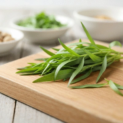 Fresh tarragon leaves used in a culinary setting, perhaps garnishing a dish or being chopped on a cutting board, high-quality food photography, no text, no words, no typography, no labels, clean image